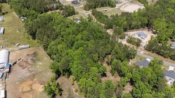 an aerial view of residential house with outdoor space and trees all around