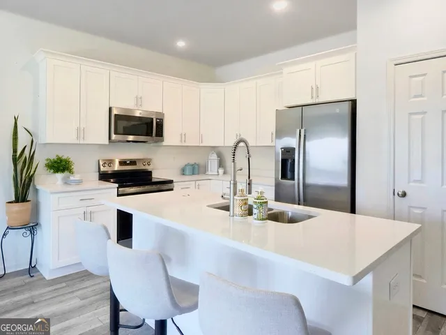 a kitchen with stainless steel appliances kitchen island a refrigerator a stove a sink a dining table and chairs