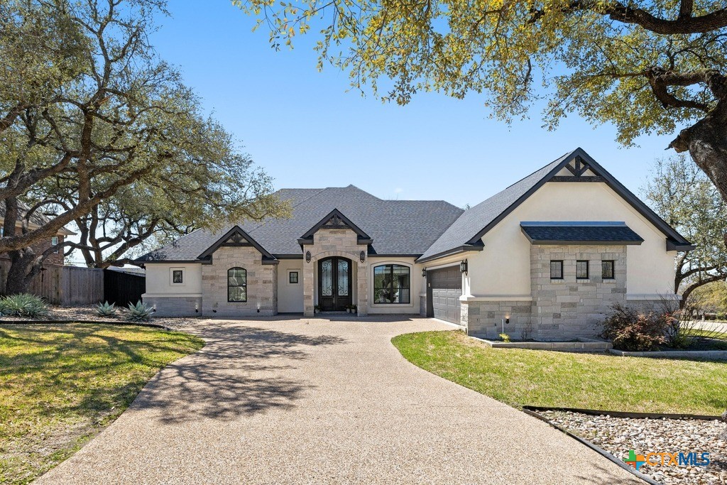 a front view of a house with a yard and large tree