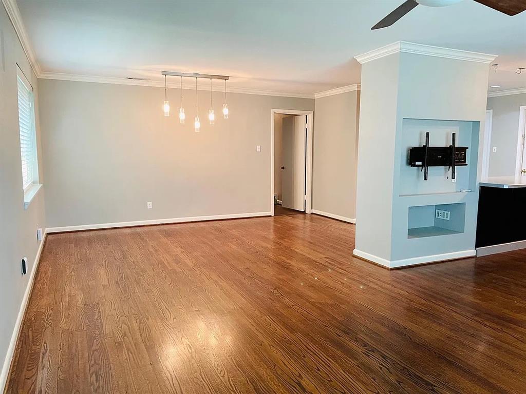 3152 Walnut Hill Lane Dallas, TX 75229 - Photo 7 of 18 a view of an empty room with wooden floor and a kitchen