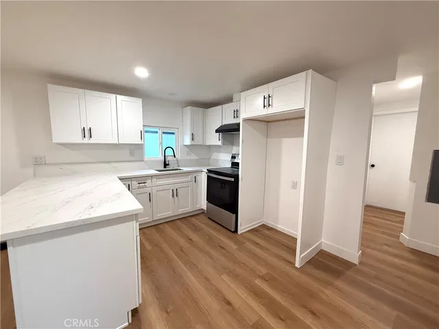 a kitchen with a sink a refrigerator a white cabinets and wooden floor