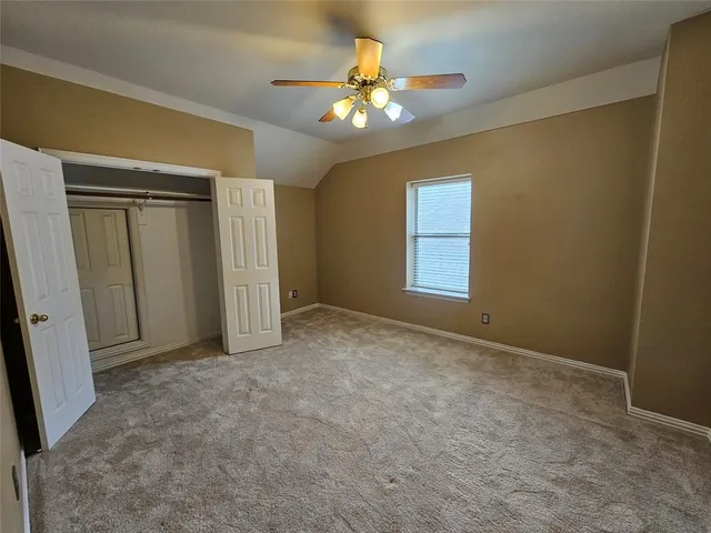 a view of an empty room with a chandelier fan