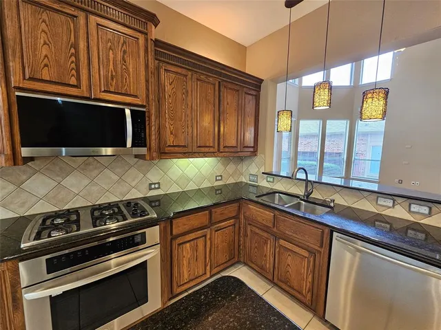 a kitchen with stainless steel appliances granite countertop a stove a sink and a microwave