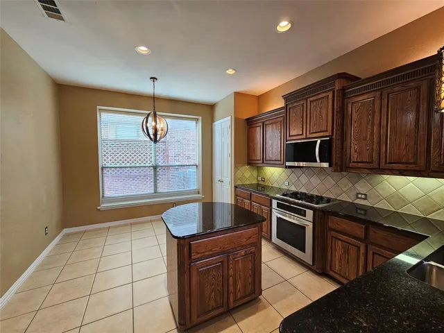 a kitchen with stainless steel appliances granite countertop a stove a sink and a microwave