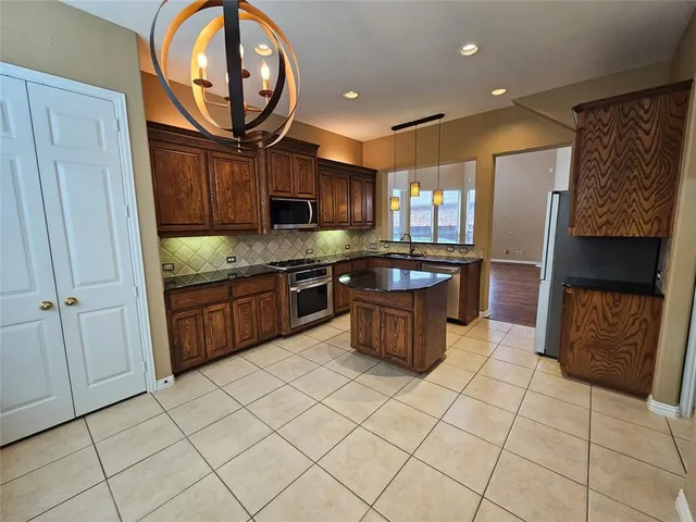 a kitchen with stainless steel appliances granite countertop a stove top oven a sink a counter top space cabinets and a window