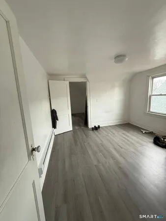 a view of an empty room with wooden floor and stairs