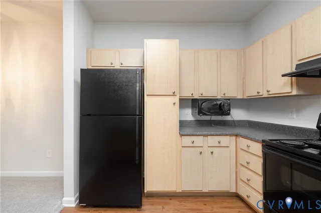 a kitchen with granite countertop white cabinets and refrigerator