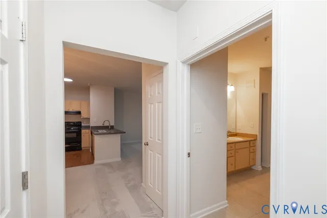 a view of a hallway with wooden floor and a bathroom