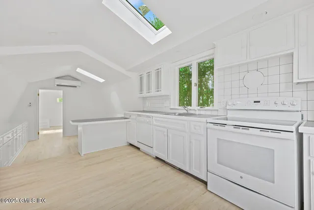 a kitchen with white cabinets and window