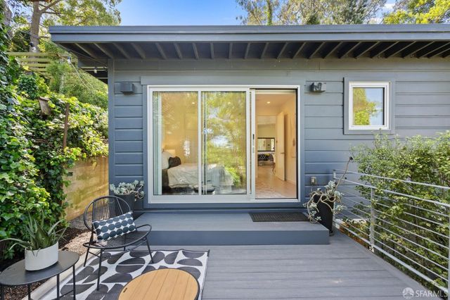 a wooden bench sitting in backside of a house with large trees and wooden floor