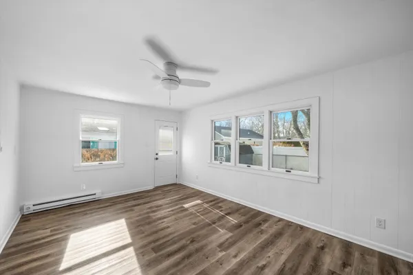 a view of an empty room with a window and wooden floor
