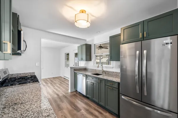 a kitchen with stainless steel appliances granite countertop a refrigerator a stove and a sink