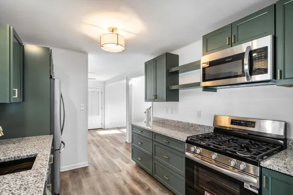 a kitchen with stainless steel appliances granite countertop a stove and a wooden floor