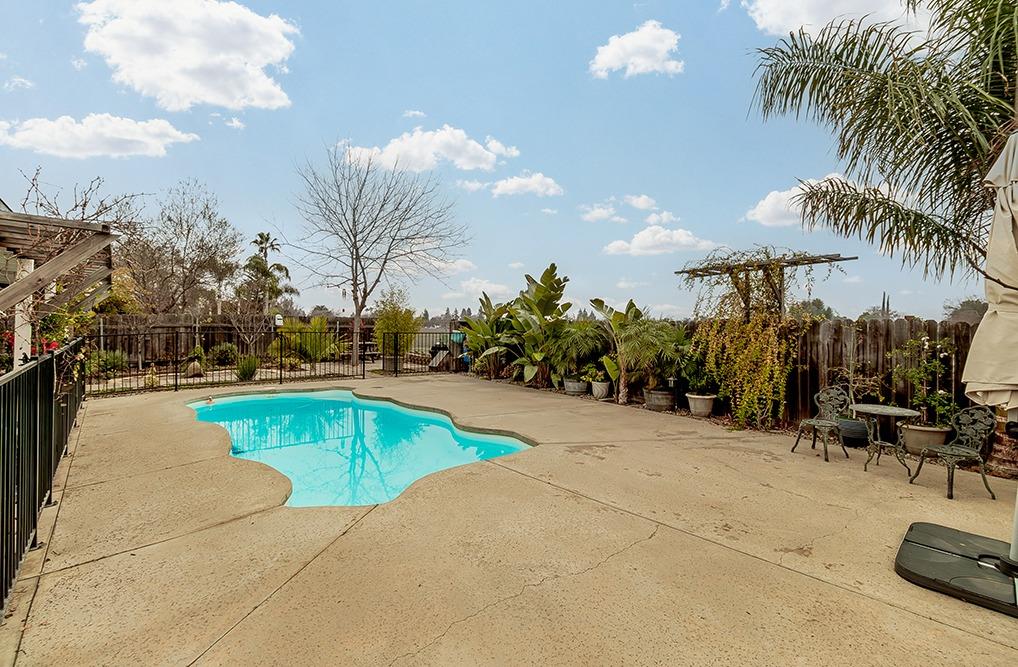 3012 Stanford Avenue Clovis, CA 93611 - Photo 28 of 41 a view of a swimming pool with a lawn chairs under an umbrella