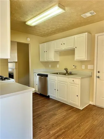 a kitchen with a sink a stove cabinets and wooden floor