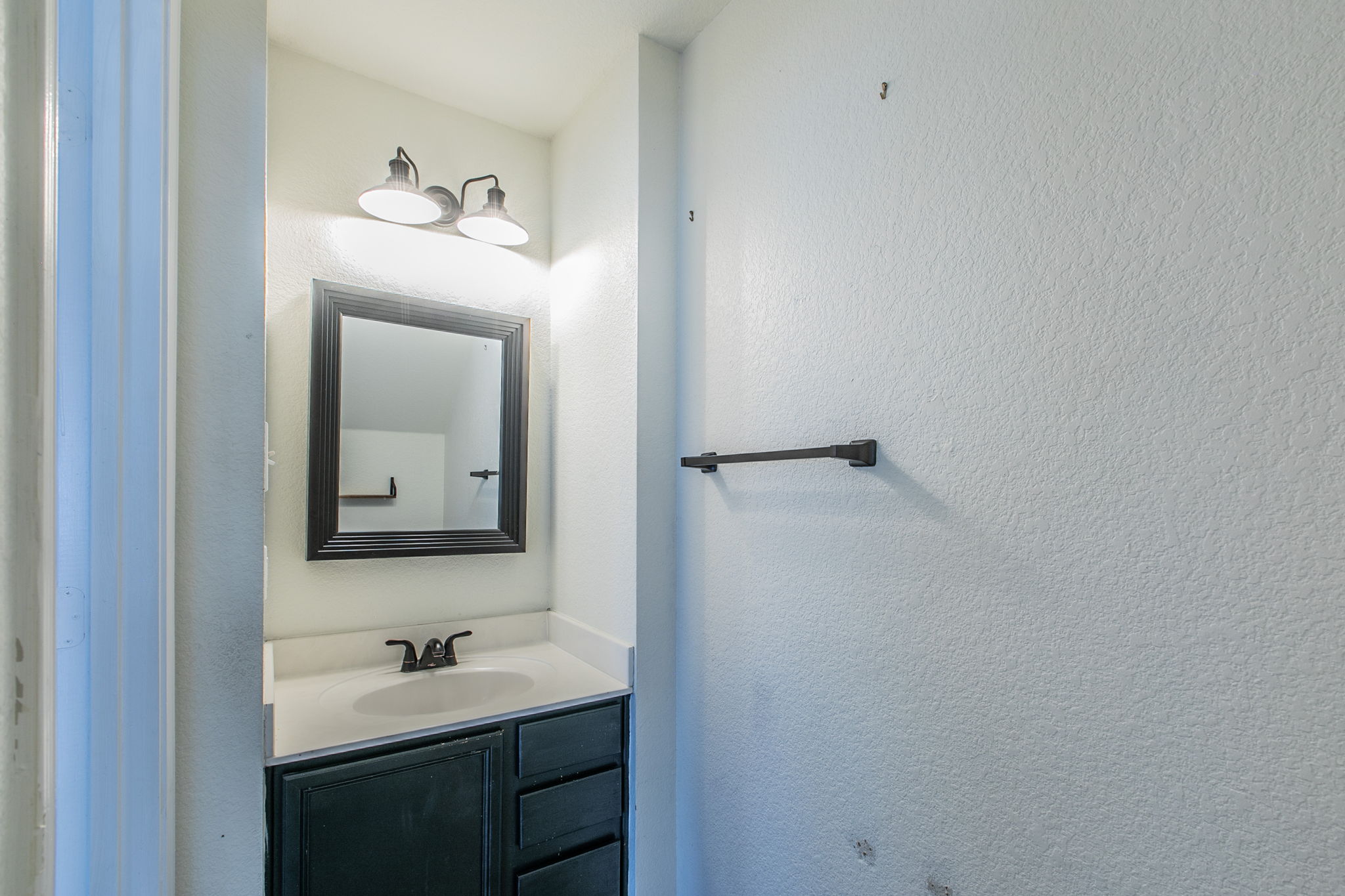 157 Lex Word Kyle, TX 78640 - Photo 29 of 34 A classic vanity setup features a dark cabinet paired with clean white countertops.