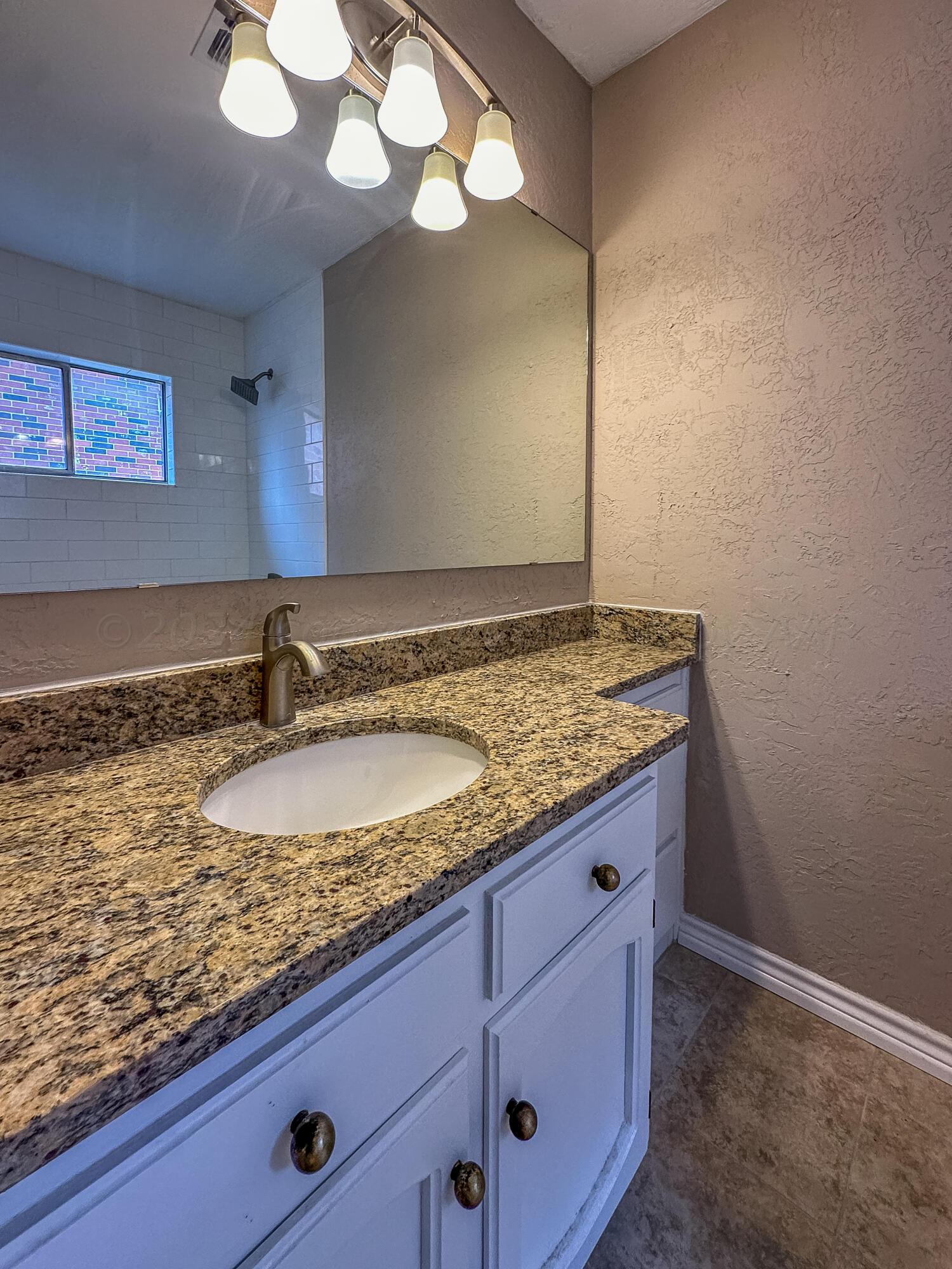 1103 Madison Street Borger, TX 79007 - Photo 13 of 16 a bathroom with a granite countertop sink and a mirror