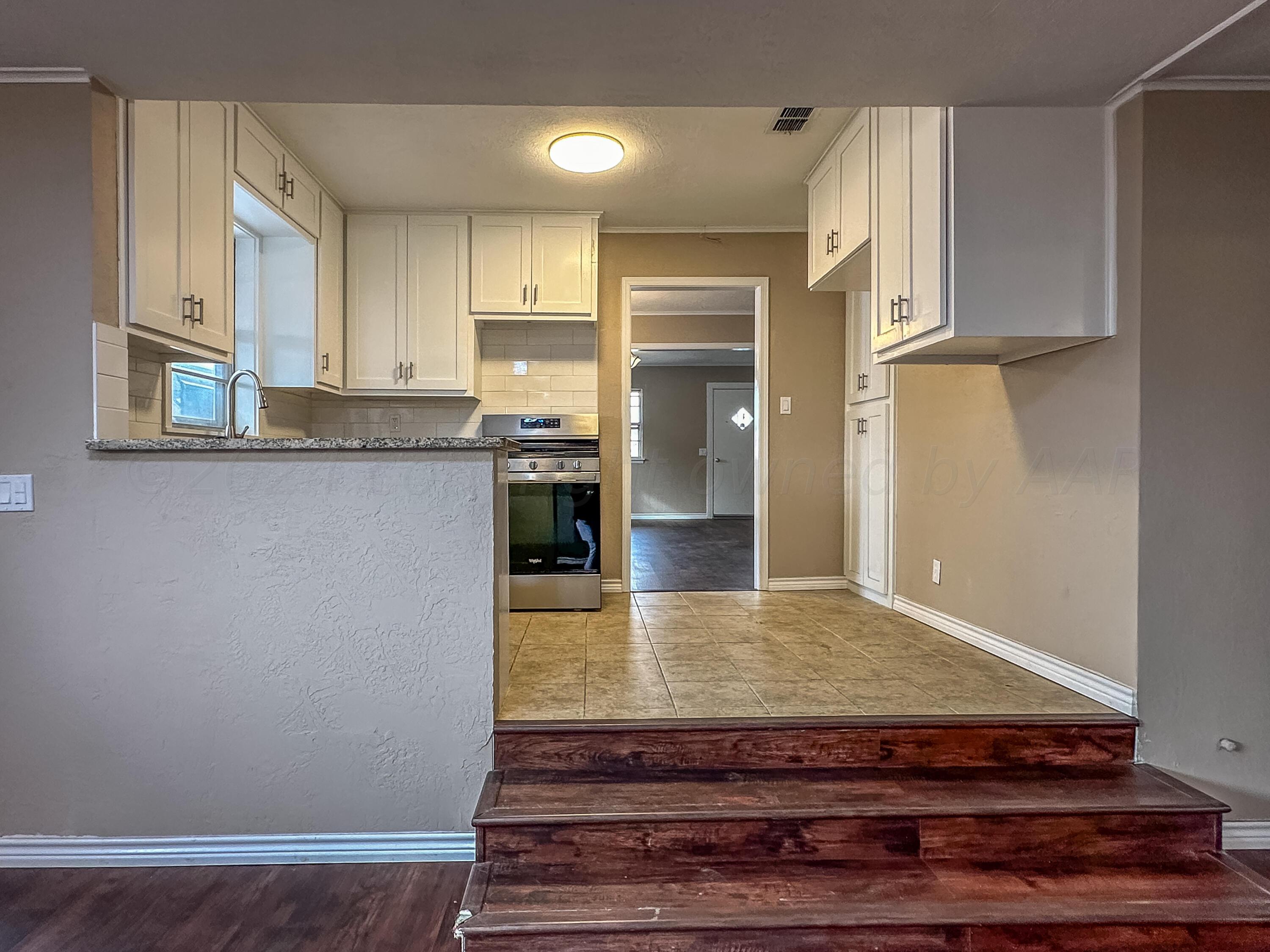 1103 Madison Street Borger, TX 79007 - Photo 15 of 16 a kitchen with kitchen island granite countertop wooden cabinets and a sink