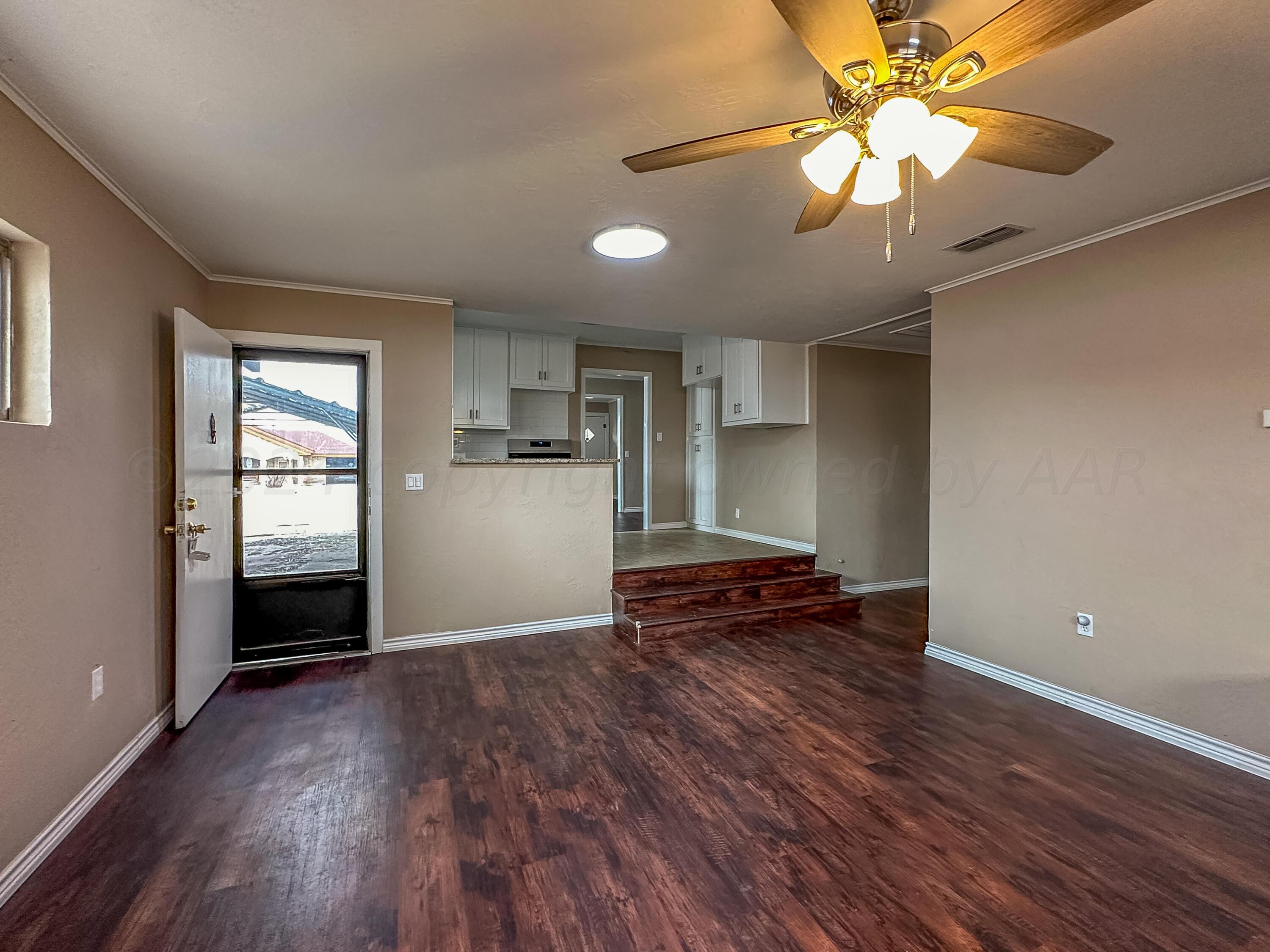 1103 Madison Street Borger, TX 79007 - Photo 4 of 16 an empty room with wooden floor chandelier fan and windows