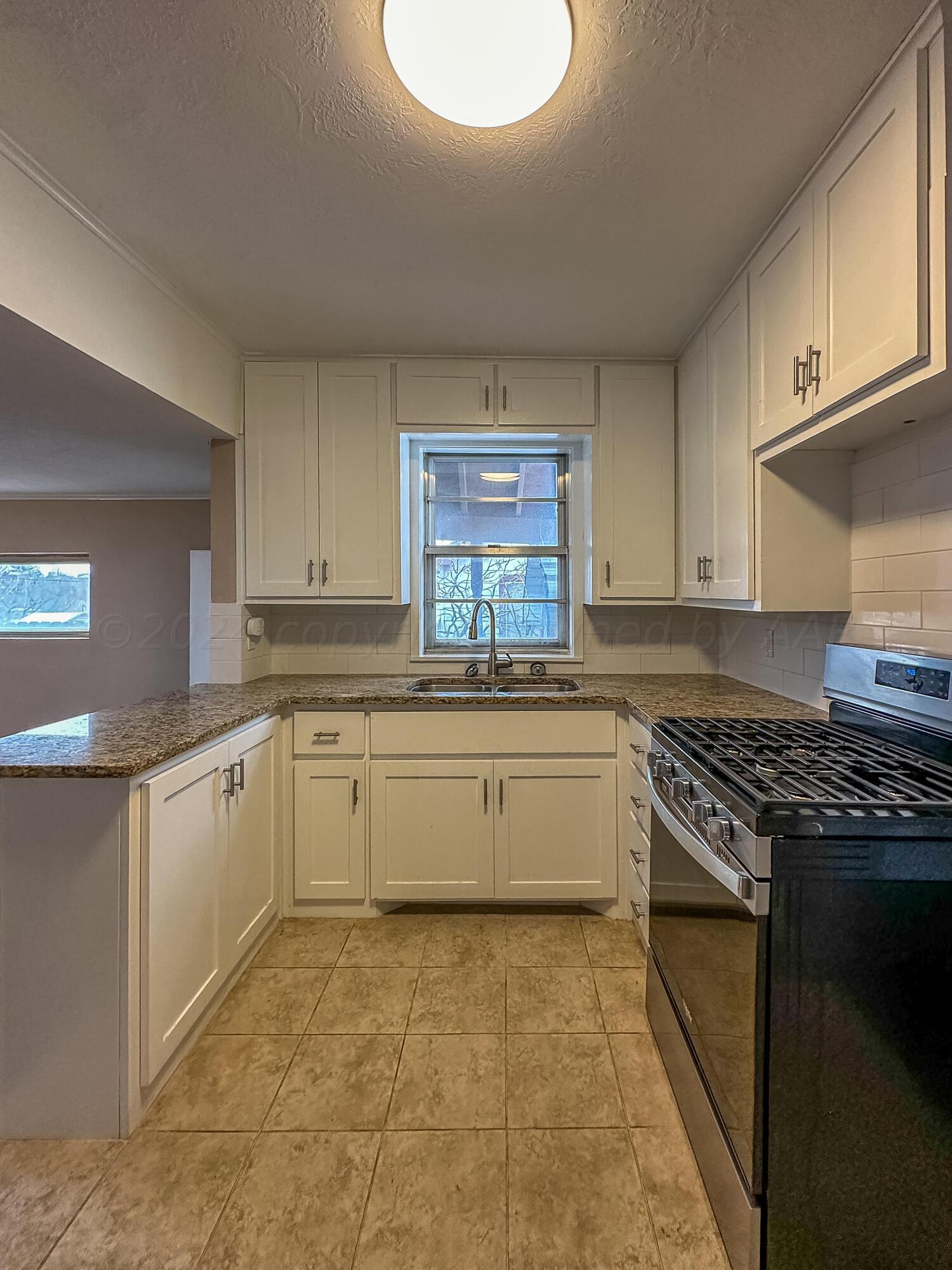 1103 Madison Street Borger, TX 79007 - Photo 5 of 16 a kitchen with a stove sink and cabinets