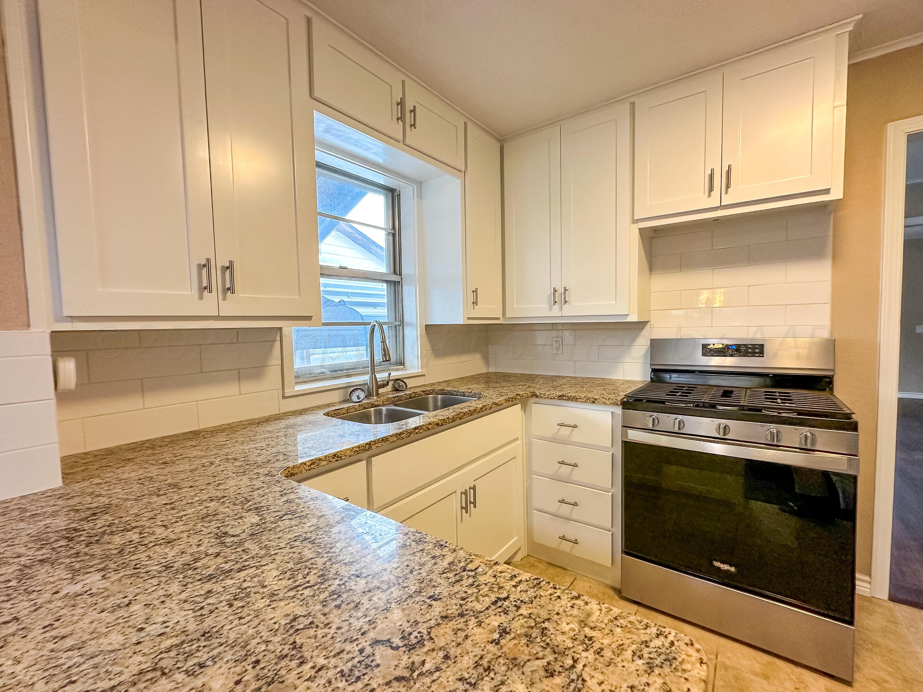 1103 Madison Street Borger, TX 79007 - Photo 6 of 16 a kitchen with a stove and white cabinets