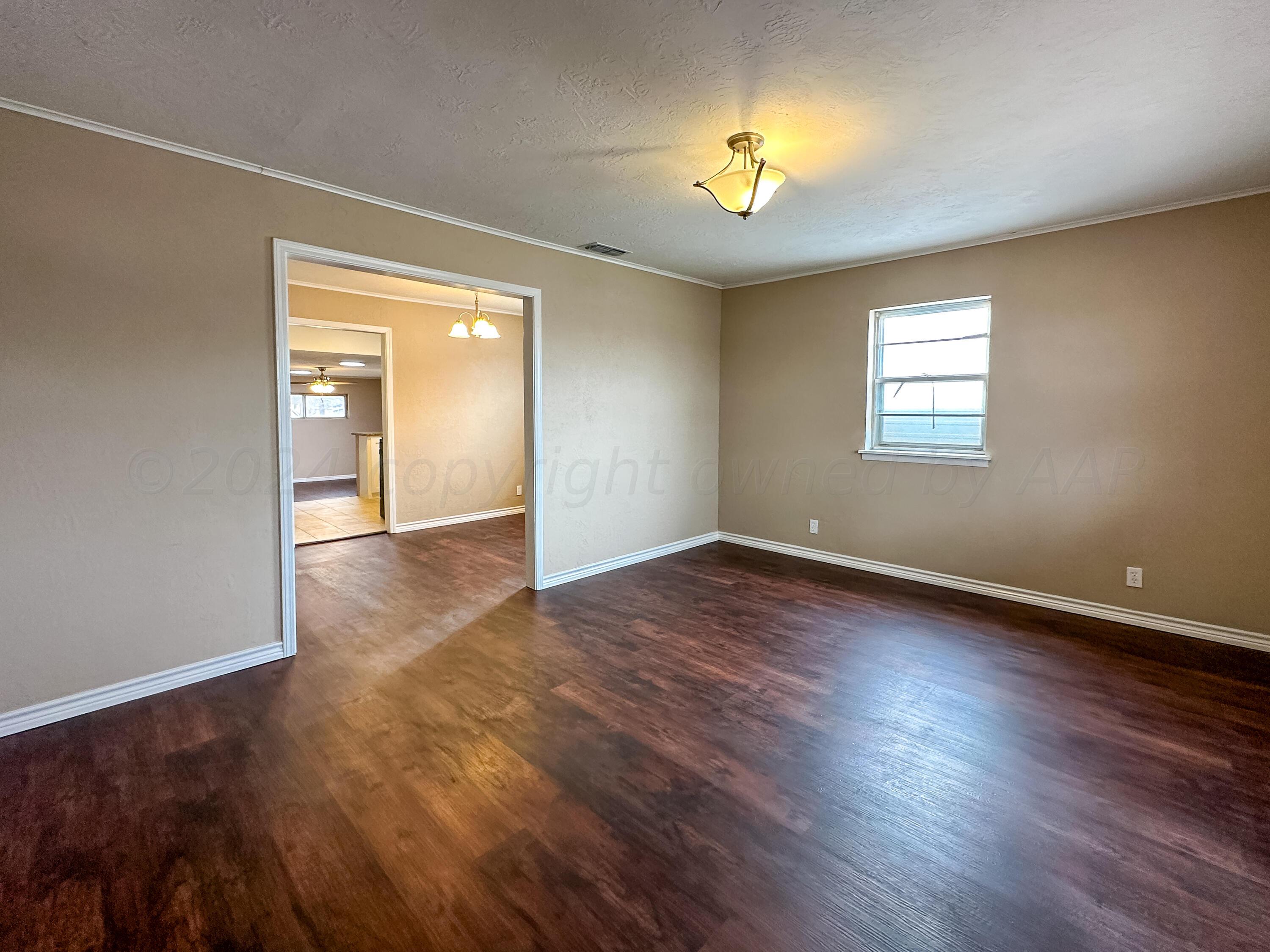 1103 Madison Street Borger, TX 79007 - Photo 9 of 16 an empty room with wooden floor and windows