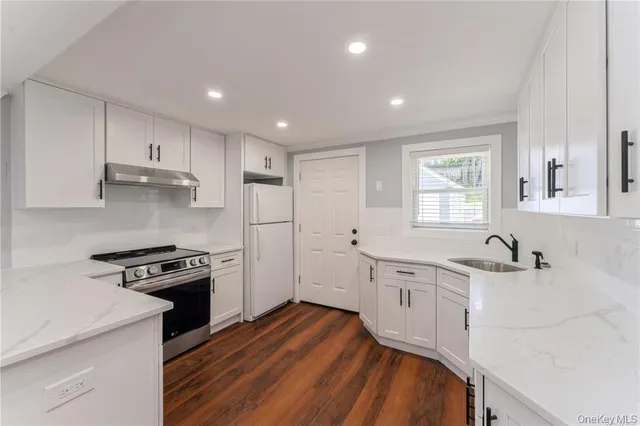 a kitchen with granite countertop a sink a stove a refrigerator and white cabinets
