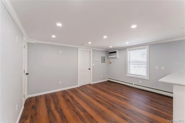 a view of an empty room with wooden floor and window
