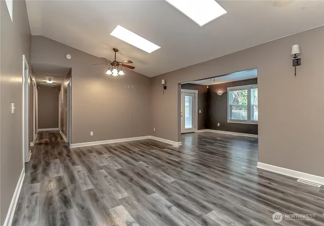 a view of an empty room with window and wooden floor