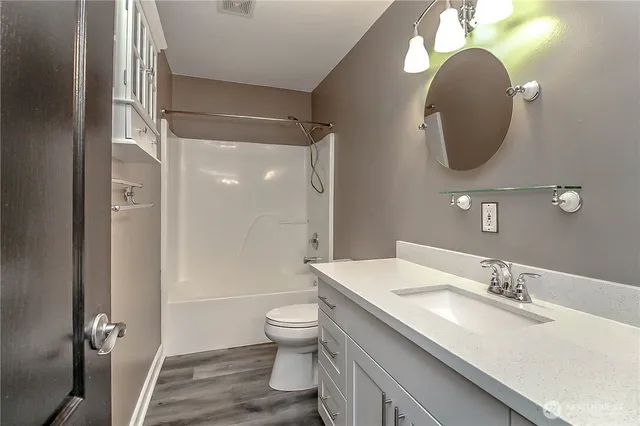 a bathroom with a granite countertop toilet sink and mirror