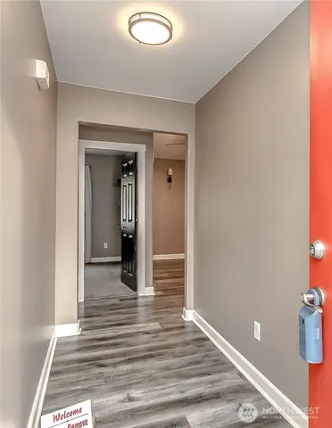 a view of a hallway with wooden floor and a bathroom
