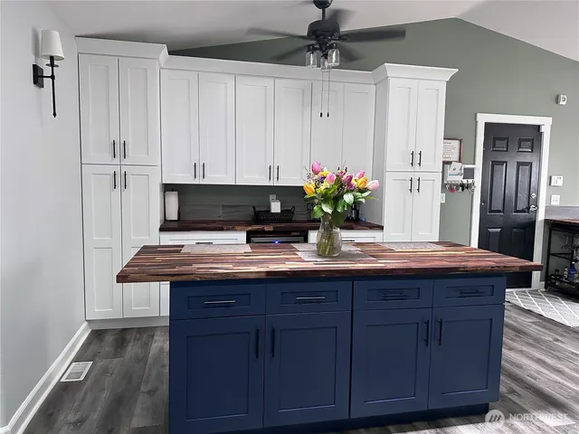 a room with kitchen island granite countertop wooden cabinets and white appliances