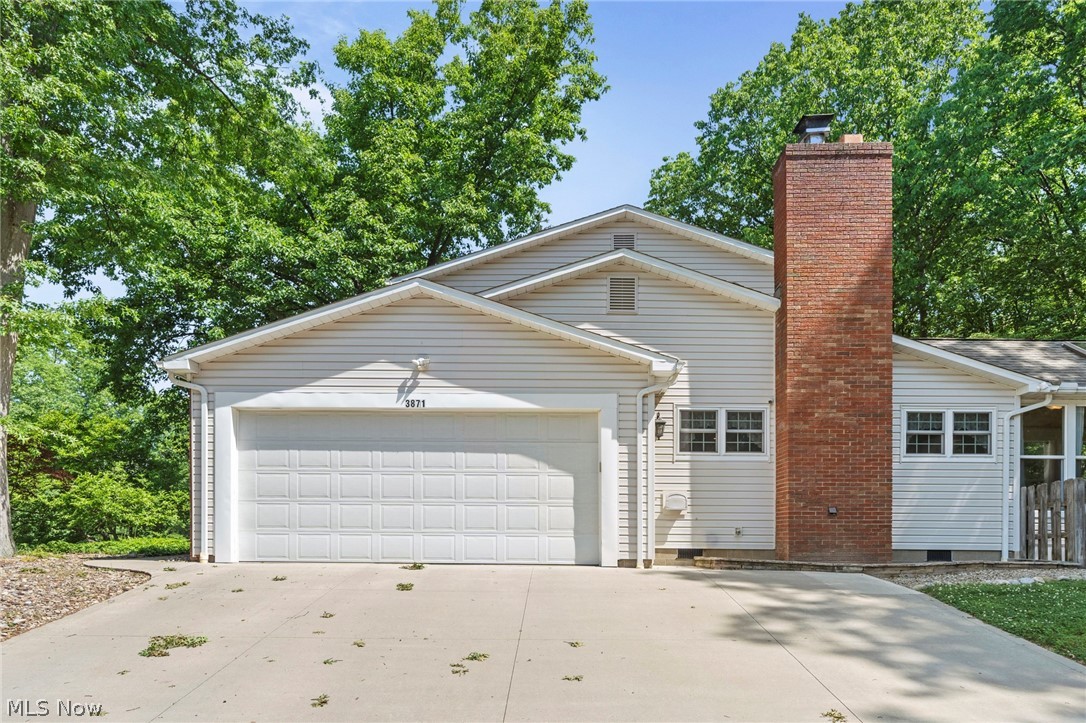 3871 Greentree Road Stow, OH 44224 - Photo 42 of 50 Cream-colored siding exterior featuring an attached two-car garage, brick chimney, and multi-pane windows