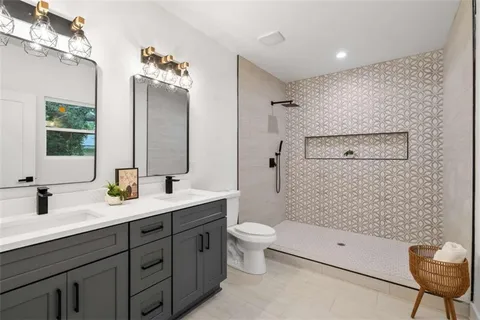 a bathroom with a double vanity sink toilet mirror and shower