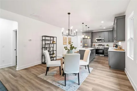 a view of a dining room and livingroom with furniture wooden floor a chandelier