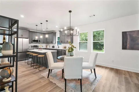 a dining room with stainless steel appliances kitchen island granite countertop a dining table chairs and granite counter tops