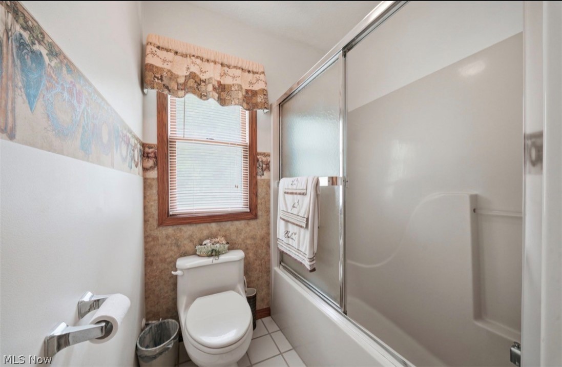3556 Lake Road Conneaut, OH 44030 - Photo 28 of 39 Bathroom featuring a window with wood trim, a toilet, and a combined tub and shower with sliding glass doors