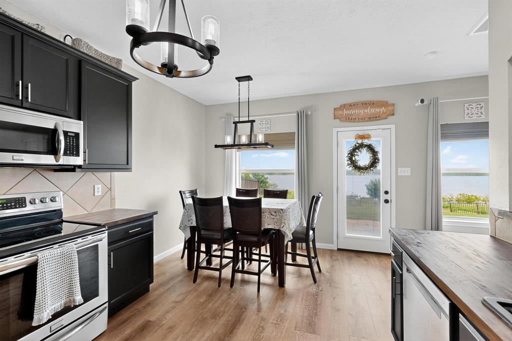 2820 Appaloosa Court Little Elm, TX 75068 - Photo 5 of 40 a kitchen with stainless steel appliances granite countertop a kitchen island hardwood floor sink stove dining table and chairs