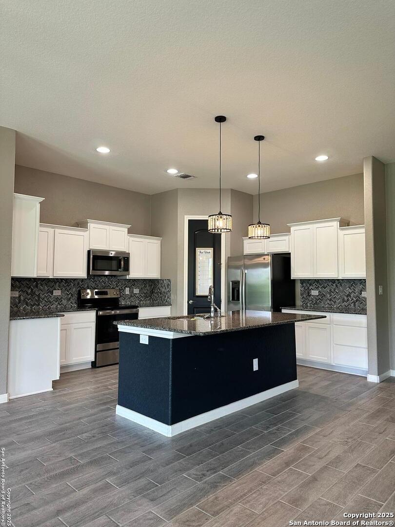 218 Iron Gate Pleasanton, TX 78064 - Photo 2 of 15 a kitchen with stainless steel appliances kitchen island granite countertop a stove and a sink