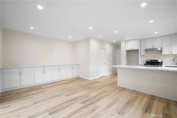 a view of a kitchen with kitchen island a sink wooden floor and stainless steel appliances