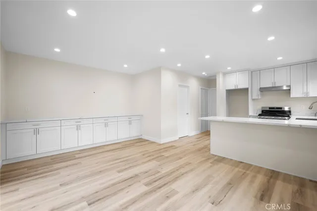 a view of a kitchen with kitchen island a sink wooden floor and stainless steel appliances