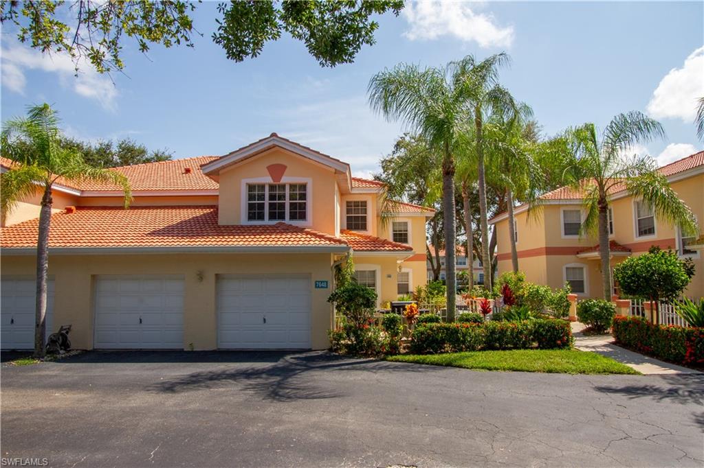 7648 Oleander Gate Drive, Unit 202 Naples, FL 34109 - Photo 1 of 23 a front view of a house with a garden and trees