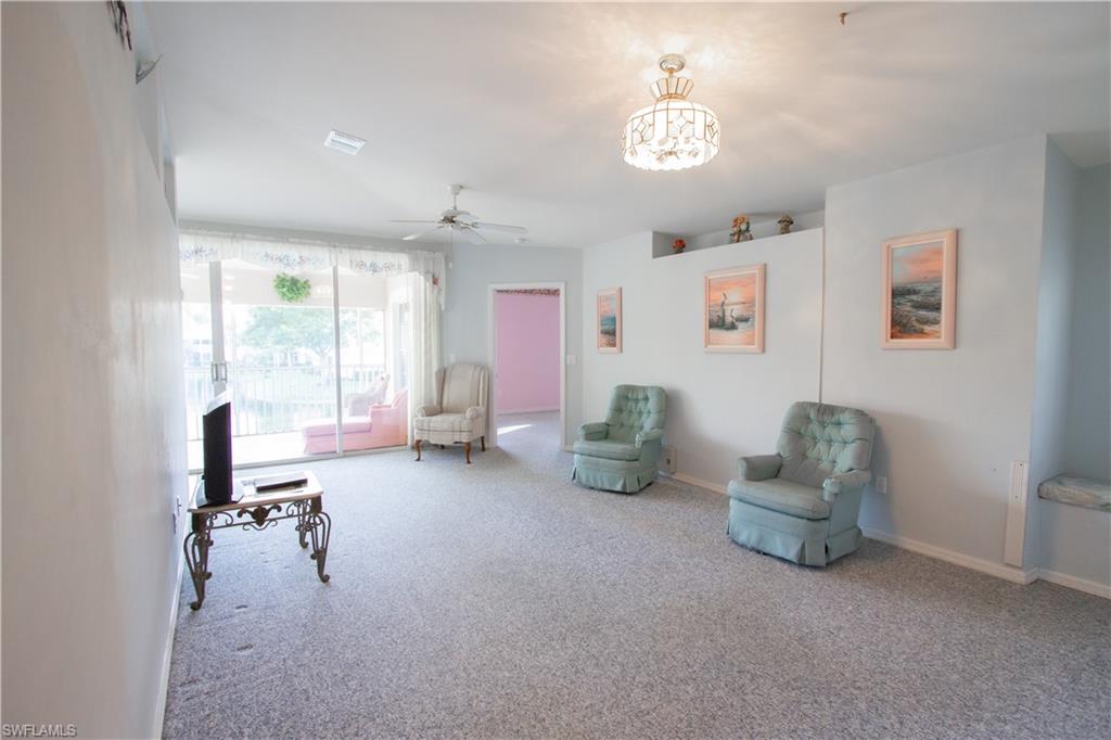 7648 Oleander Gate Drive, Unit 202 Naples, FL 34109 - Photo 12 of 23 a living room with furniture and a chandelier