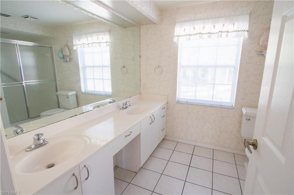 7648 Oleander Gate Drive, Unit 202 Naples, FL 34109 - Photo 13 of 23 a spacious bathroom with a double vanity sink a mirror and a bathtub