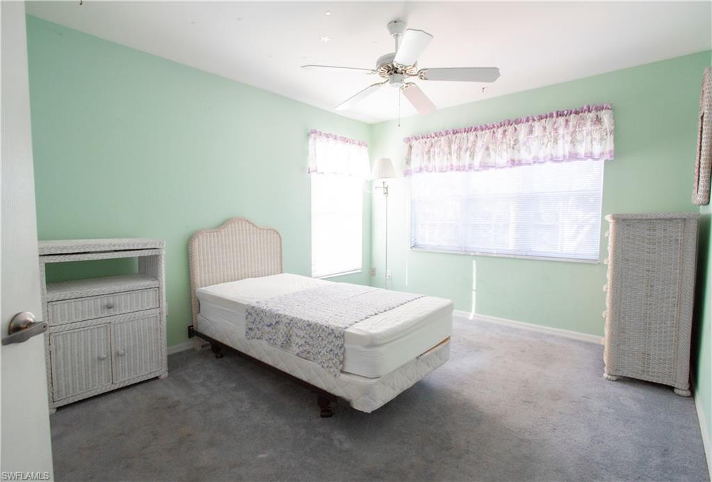 7648 Oleander Gate Drive, Unit 202 Naples, FL 34109 - Photo 15 of 23 a bedroom with a bed and a chandelier
