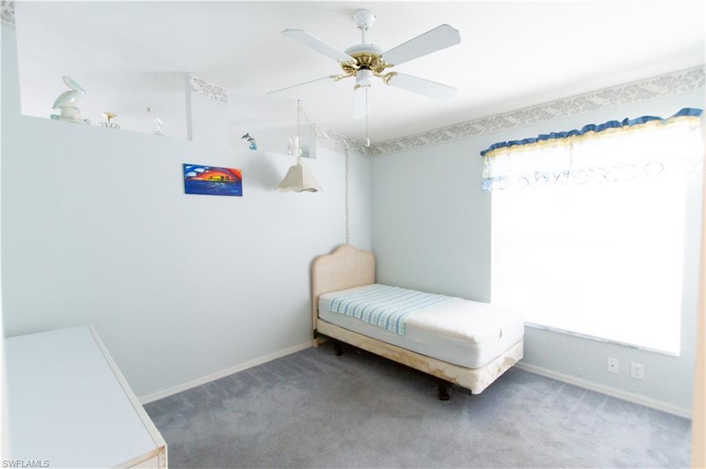 7648 Oleander Gate Drive, Unit 202 Naples, FL 34109 - Photo 16 of 23 a bedroom with a bed and a chandelier