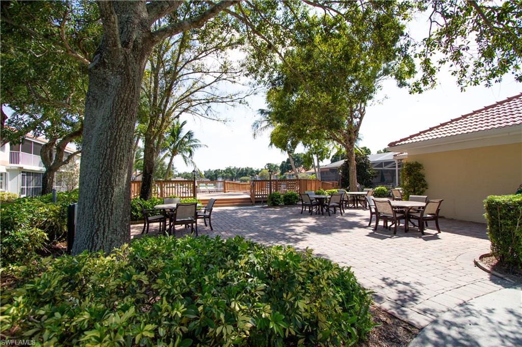 7648 Oleander Gate Drive, Unit 202 Naples, FL 34109 - Photo 21 of 23 a view of a bench in a backyard with a large tree