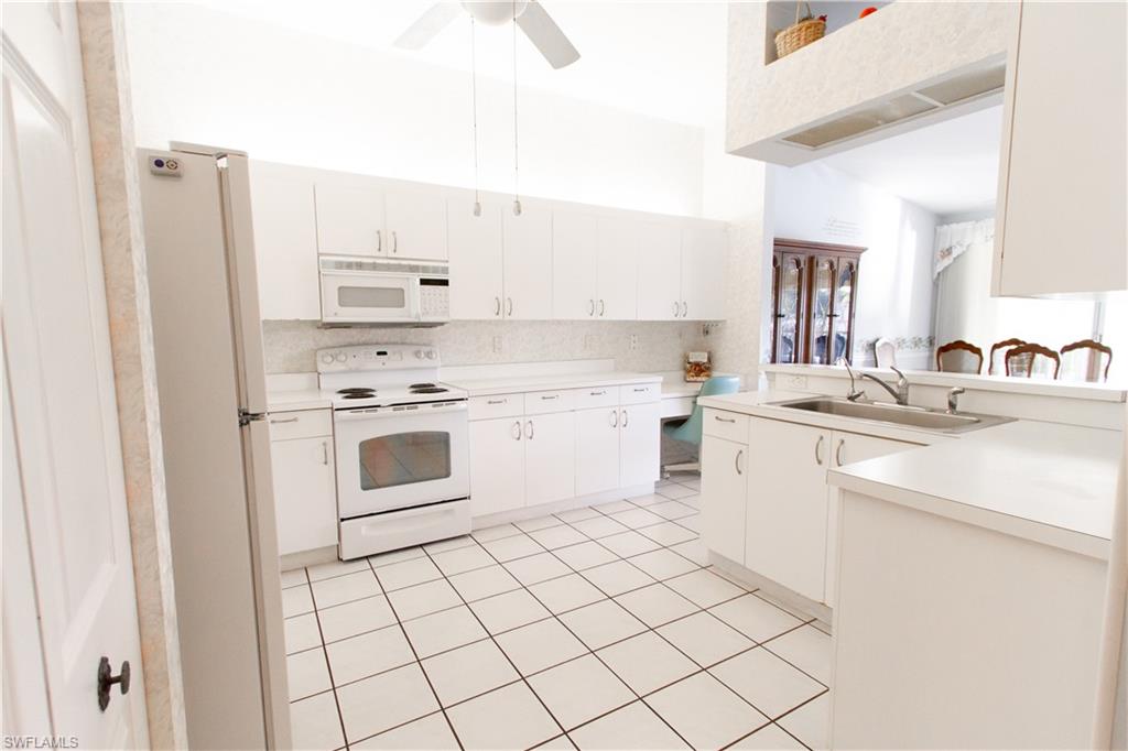 7648 Oleander Gate Drive, Unit 202 Naples, FL 34109 - Photo 7 of 23 a kitchen with white cabinets and white appliances