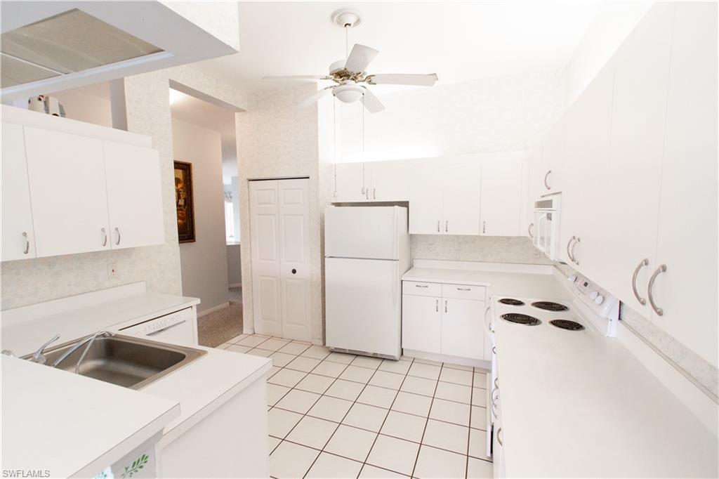 7648 Oleander Gate Drive, Unit 202 Naples, FL 34109 - Photo 8 of 23 a kitchen with a refrigerator and a sink