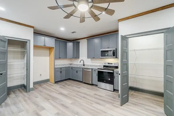 a kitchen with stainless steel appliances granite countertop a refrigerator a sink dishwasher a stove and white cabinets with wooden floor